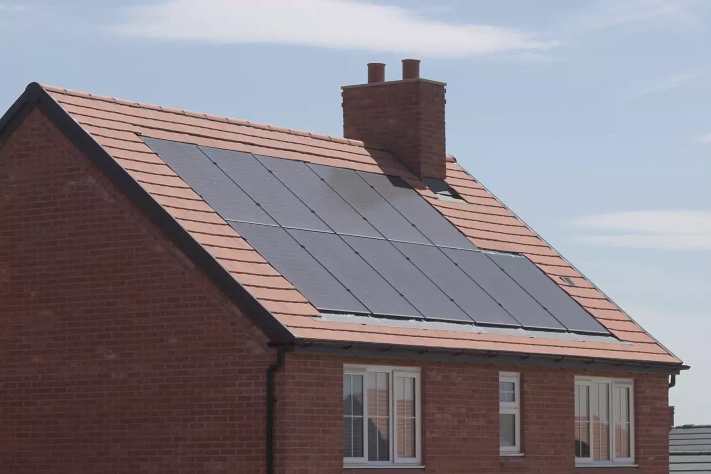 Solar panels installed on the tiled roof of a brick house